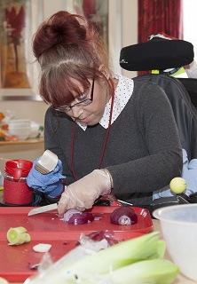 Pendine Park's Enrichment coordinator Elaine Lee has started a cooking club for residents to enjoy. Pictured: Sian Walley prepares the onion